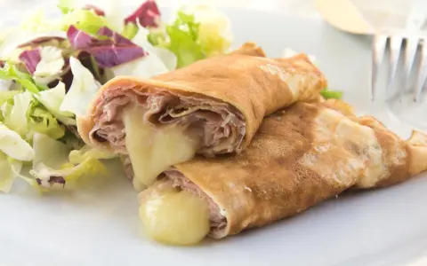 Herzhafte Pfannkuchen gefüllt mit Schinken und geschmolzenem Käse, serviert mit einem frischen Salat.