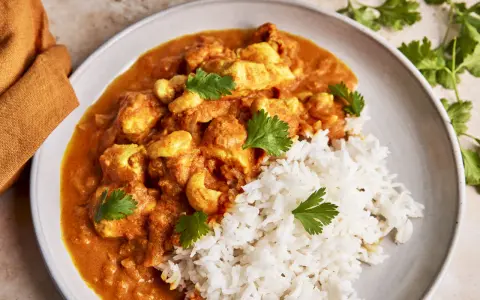 Cremiges Chicken Korma mit Basmatireis und frischem Koriander. Ein köstliches indisches Gericht, das zum Genießen einlädt.
