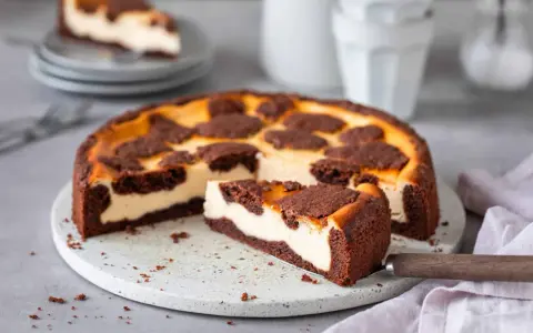 Ein saftiger russischer Zupfkuchen mit cremigem Käsekuchen und schokoladigen Streuseln. Ein Stück wurde bereits herausgeschnitten.