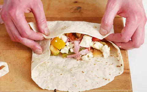 Hände falten wraps mit Gemüse, Schinken und Käse.