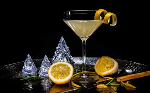 Ein eleganter French 75 Cocktail mit Zitronenzeste, dekoriert mit Kristallbäumen und Rosmarin.