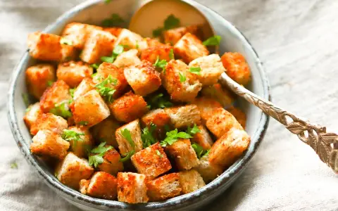 Goldbraune, knusprige Croutons, frisch zubereitet, garniert mit Petersilie in einer Schüssel. Perfekt zum **Croutons selber machen** für Salate oder Suppen.