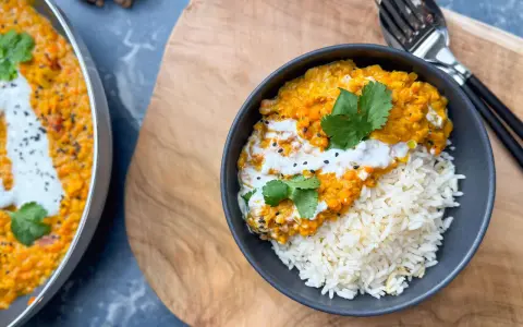 Herzhafte Linsen Rezepte: Cremiges Dal mit Reis, garniert mit Koriander und Kokosmilch. Ein köstliches Gericht, das Wärme und Geschmack vereint.
