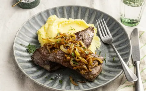 Leber braten mit karamellisierten Zwiebeln und Kartoffelpüree auf einem grauen Teller. Ein Klassiker, der immer schmeckt.