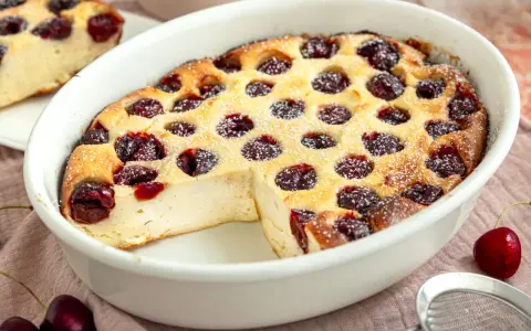 Ein goldbrauner Kirschauflauf mit Puderzucker bestäubt, bereit zum Servieren. Dieses Kirschauflauf Rezept ist ein Genuss!