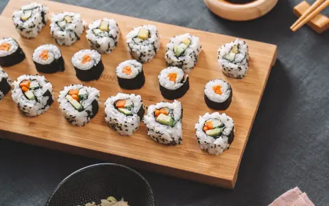 Selbstgemachtes Sushi mit Karotten und Gurken auf einem Holzbrett. So einfach kann Sushi selber machen sein!