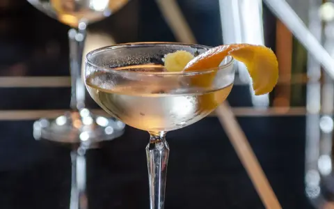Ein klassischer James Bond Vesper Martini, garniert mit einer Zitronenzeste, in einem eleganten Glas.