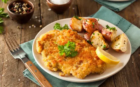 Goldbraunes Schnitzel, perfekt paniert, mit Rosmarinkartoffeln und Zitrone. Die richtige **Schnitzel panieren Reihenfolge** macht's möglich!