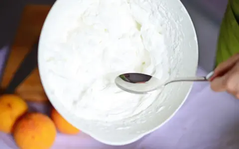 Eine Schüssel mit frisch geschlagener Sahne, bereit für ein Dessert. Ein Löffel ruht in der luftigen Masse.