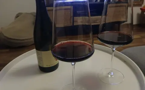 Zwei Gläser Rotwein und eine Flasche Wein, die an die Beaujolais-Region erinnert, stehen auf einem weißen Tablett.