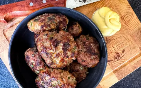 Leckeres Buletten Rezept: Saftige Frikadellen in einer Schüssel, daneben Senf und ein Messer. Perfekt für den Grill oder die Pfanne.