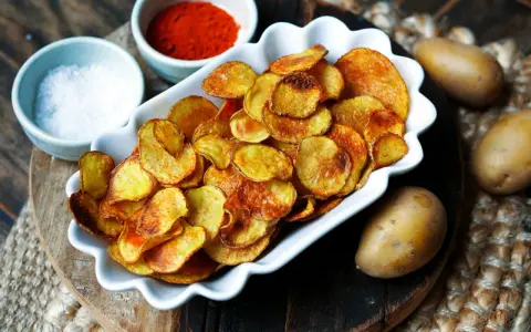 Selbstgemachte Kartoffelchips, goldbraun und knusprig, mit Salz und Paprikapulver. So einfach ist kartoffelchips selber machen!