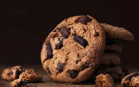 Ein Stapel saftiger american cookies mit Schokoladenstückchen auf einem Holztisch.