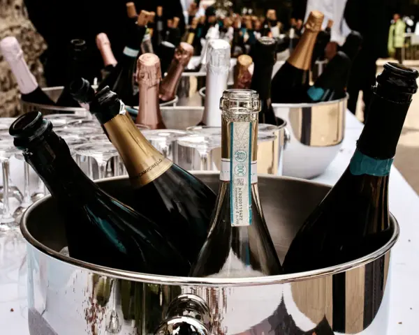 Mehrere Flaschen Sekt in einem silbernen Eiskübel, bereit für die Feier. Gläser stehen daneben.