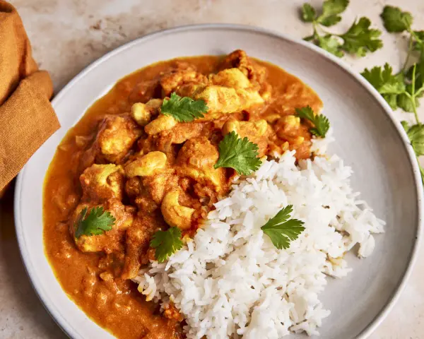 Cremiges Chicken Korma mit Basmatireis und frischem Koriander. Ein köstliches indisches Gericht, das zum Genießen einlädt.