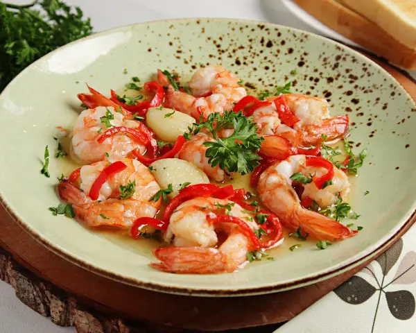 Garnelen in Knoblauchöl mit Paprika und Petersilie, ein köstliches Gericht, das perfekt zu einem Glas Wein passt.