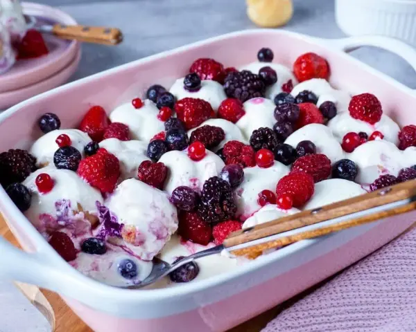 Cremiger Windbeutel-Dessert-Auflauf mit frischen Beeren wie Himbeeren, Blaubeeren und Brombeeren.