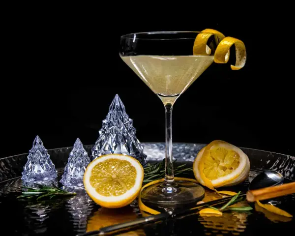 Ein eleganter French 75 Cocktail mit Zitronenzeste, dekoriert mit Kristallbäumen und Rosmarin.