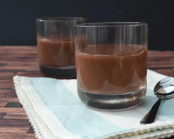 Zwei Gläser cremiger Schokopudding, perfekt zum Schokopudding selber machen. Ein Löffel liegt bereit.