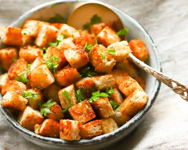 Goldbraune, knusprige Croutons, frisch zubereitet, garniert mit Petersilie in einer Schüssel. Perfekt zum **Croutons selber machen** für Salate oder Suppen.