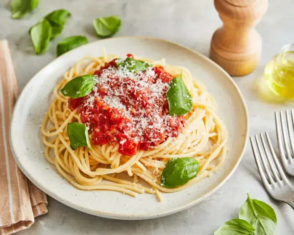 Ein Teller Spaghetti Napoli mit Tomatensauce, Parmesan und frischem Basilikum.