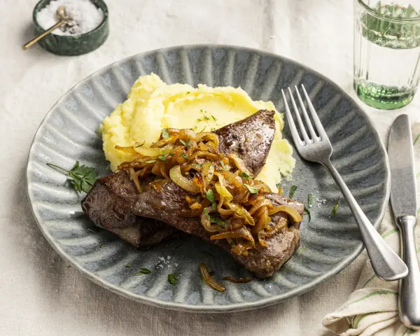 Leber braten mit karamellisierten Zwiebeln und Kartoffelpüree auf einem grauen Teller. Ein Klassiker, der immer schmeckt.