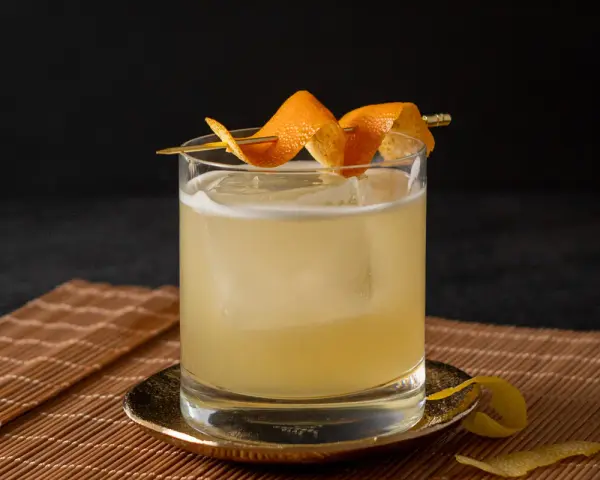 Klassisches Rezept für Gin Tonic: Ein erfrischender Drink mit Eis, garniert mit Orangenschale.