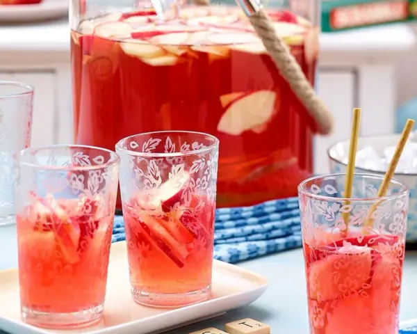 Erfrischende alkoholfreie Bowle mit Apfelstücken in Gläsern, bereit für ein sommerliches Treffen.