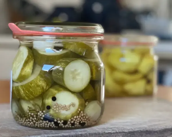 Einmachgläser mit Gurkenscheiben, Zwiebeln und Gewürzen. So werden Gurken eingelegt nach Omas Rezept.