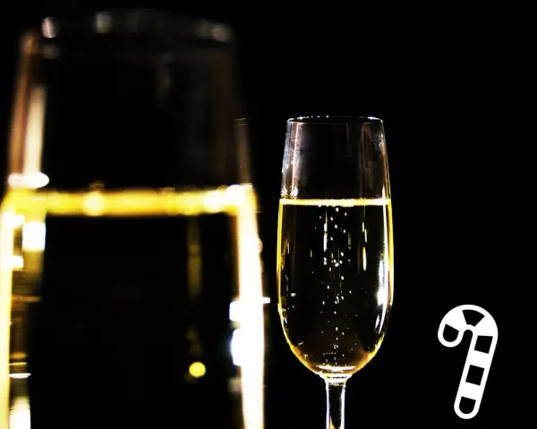 Ein Glas Champagner mit Bläschen, daneben ein Zuckerstangen-Symbol. Die richtige dosage Champagner für den festlichen Anlass.