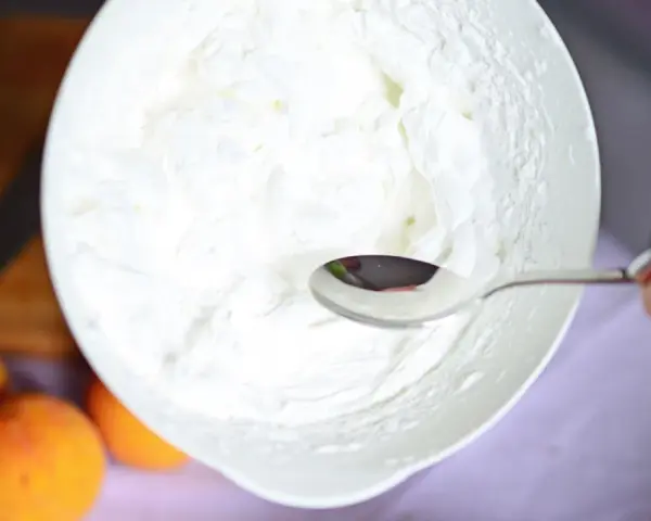 Eine Schüssel mit frisch geschlagener Sahne, bereit für ein Dessert. Ein Löffel ruht in der luftigen Masse.