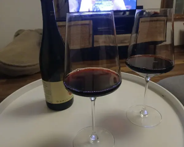 Zwei Gläser Rotwein und eine Flasche Wein, die an die Beaujolais-Region erinnert, stehen auf einem weißen Tablett.