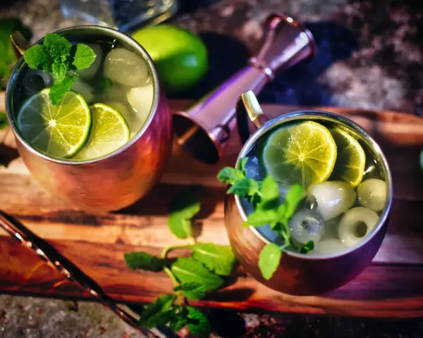 Zwei erfrischende Gin Mule Cocktails in Kupferbechern, garniert mit Limettenscheiben und Minze, bereit zum Genuss.