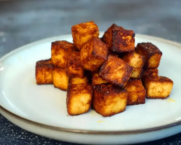 Goldbraun gebratene Tofuwürfel, perfekt zum tofu zubereiten. Knusprig und lecker auf einem Teller angerichtet.