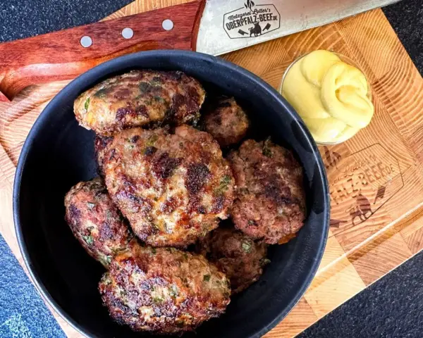 Leckeres Buletten Rezept: Saftige Frikadellen in einer Schüssel, daneben Senf und ein Messer. Perfekt für den Grill oder die Pfanne.