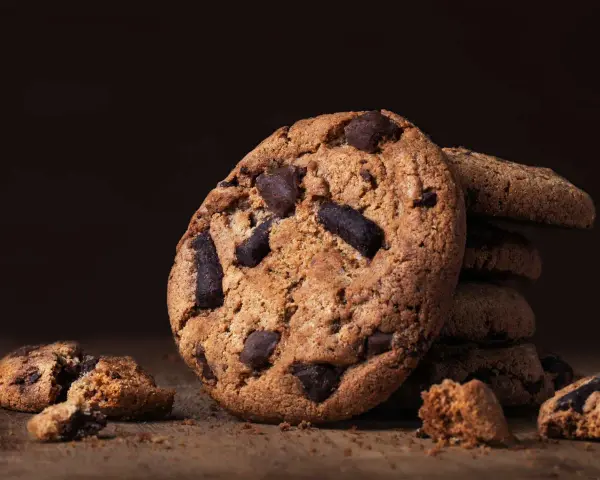 Ein Stapel saftiger american cookies mit Schokoladenstückchen auf einem Holztisch.