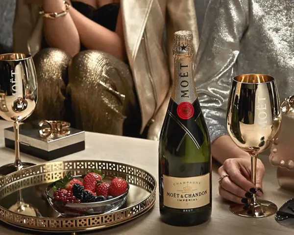 Elegante Szene mit Moët & Chandon Champagnerflasche, goldenen Gläsern und Beeren. Die Herkunft des Luxus wird durch die Marke und die festliche Atmosphäre betont.