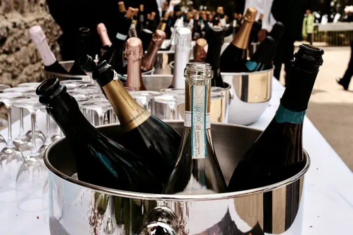 Mehrere Flaschen Sekt in einem silbernen Eiskübel, bereit für die Feier. Gläser stehen daneben.