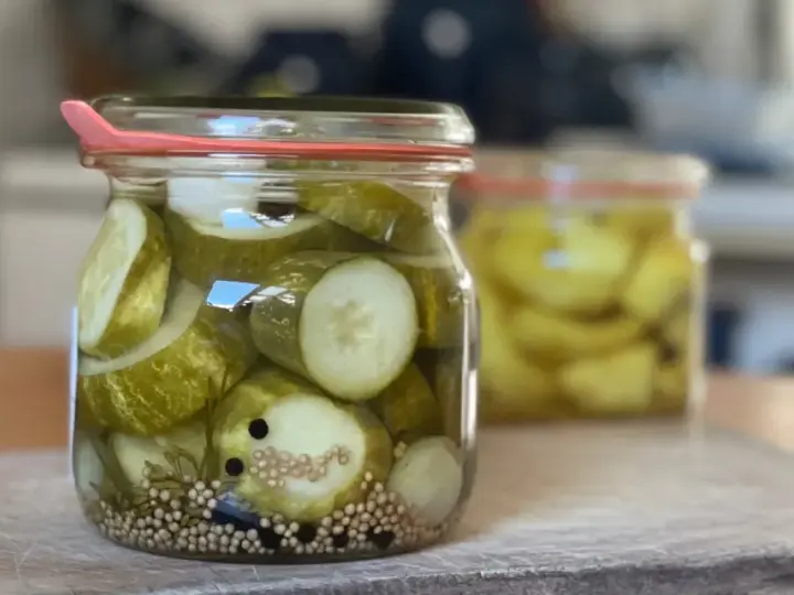 Einmachgläser mit Gurkenscheiben, Zwiebeln und Gewürzen. So werden Gurken eingelegt nach Omas Rezept.