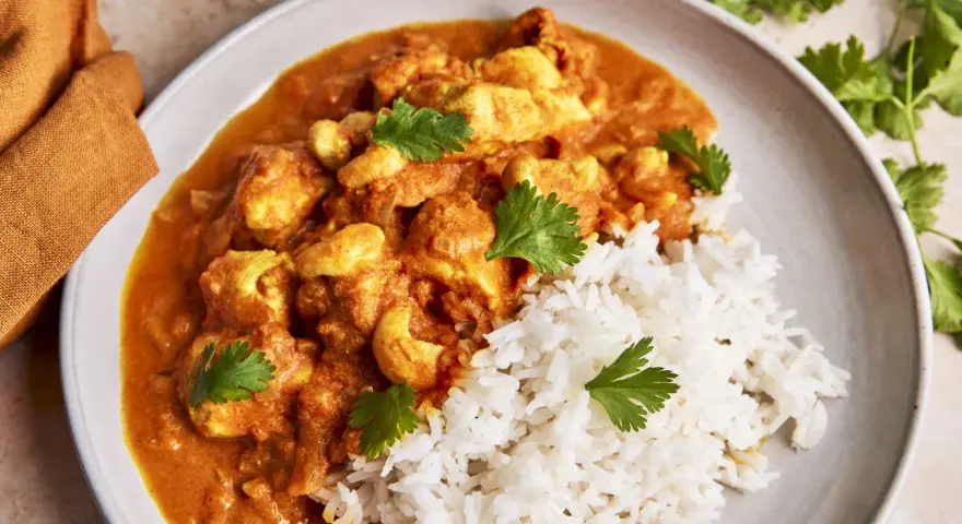 Cremiges Chicken Korma mit Basmatireis und frischem Koriander. Ein köstliches indisches Gericht, das zum Genießen einlädt.