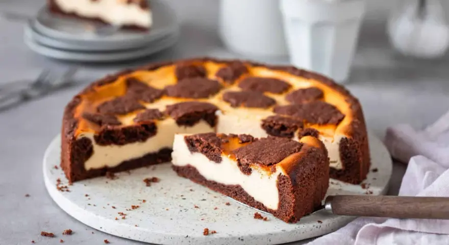Ein saftiger russischer Zupfkuchen mit cremigem Käsekuchen und schokoladigen Streuseln. Ein Stück wurde bereits herausgeschnitten.