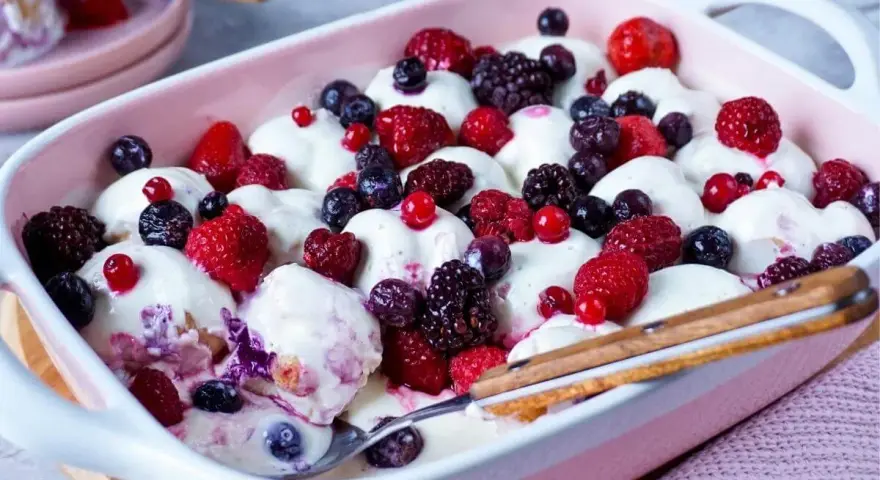 Cremiger Windbeutel-Dessert-Auflauf mit frischen Beeren wie Himbeeren, Blaubeeren und Brombeeren.