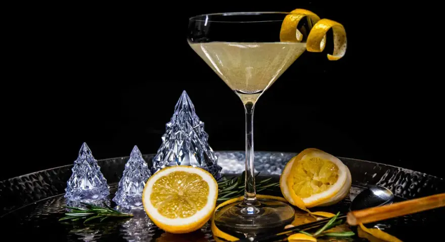 Ein eleganter French 75 Cocktail mit Zitronenzeste, dekoriert mit Kristallbäumen und Rosmarin.