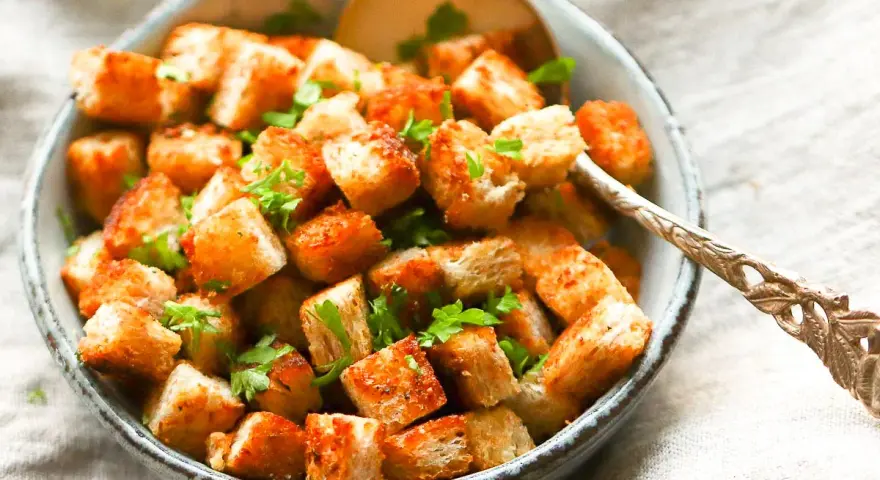 Goldbraune, knusprige Croutons, frisch zubereitet, garniert mit Petersilie in einer Schüssel. Perfekt zum **Croutons selber machen** für Salate oder Suppen.