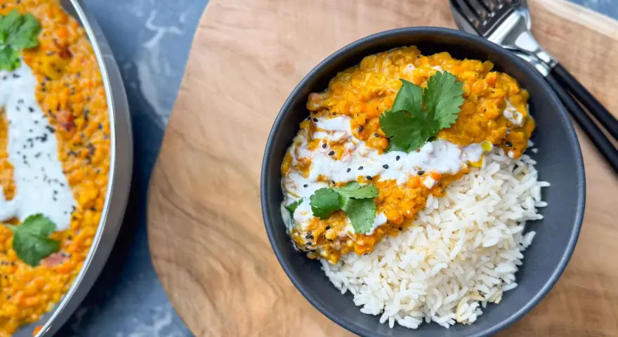 Herzhafte Linsen Rezepte: Cremiges Dal mit Reis, garniert mit Koriander und Kokosmilch. Ein köstliches Gericht, das Wärme und Geschmack vereint.