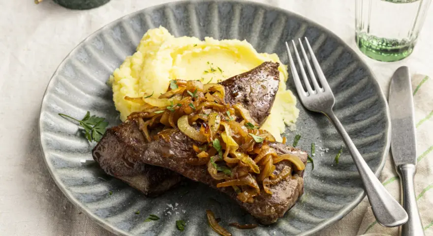 Leber braten mit karamellisierten Zwiebeln und Kartoffelpüree auf einem grauen Teller. Ein Klassiker, der immer schmeckt.