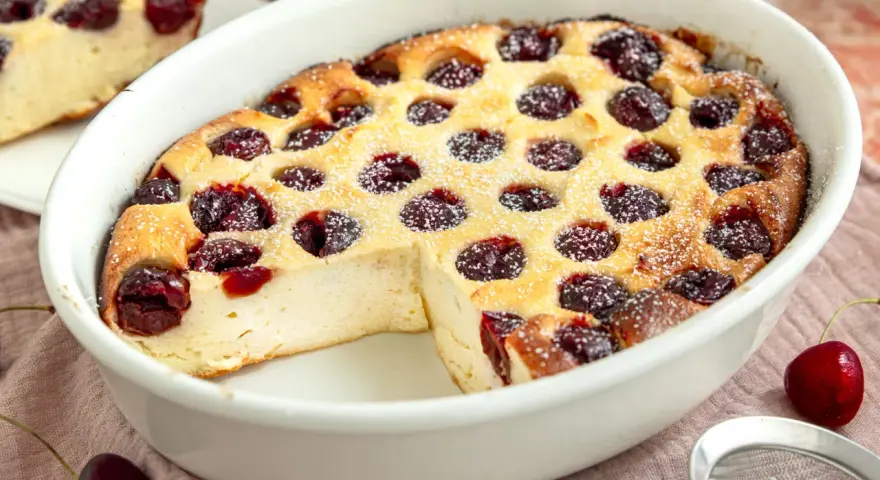Ein goldbrauner Kirschauflauf mit Puderzucker bestäubt, bereit zum Servieren. Dieses Kirschauflauf Rezept ist ein Genuss!