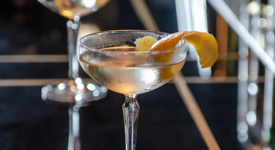 Ein klassischer James Bond Vesper Martini, garniert mit einer Zitronenzeste, in einem eleganten Glas.