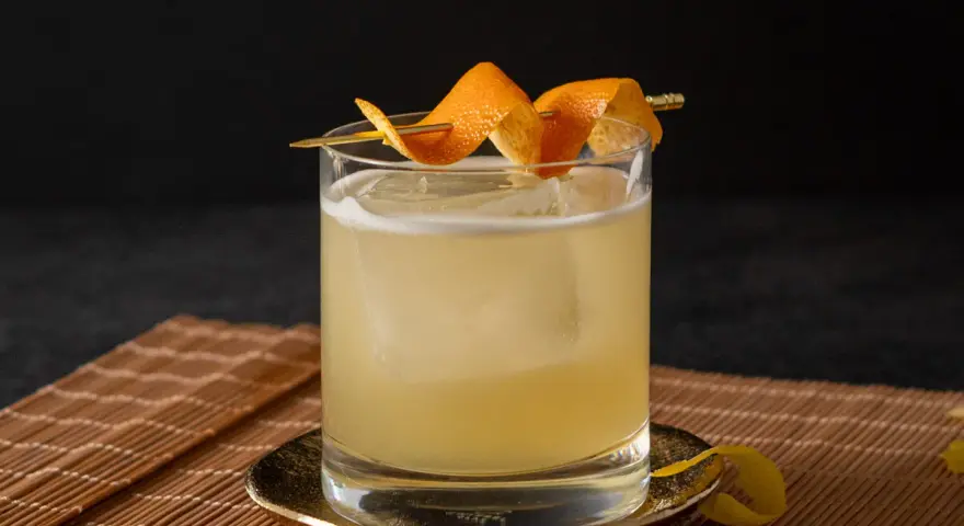 Klassisches Rezept für Gin Tonic: Ein erfrischender Drink mit Eis, garniert mit Orangenschale.