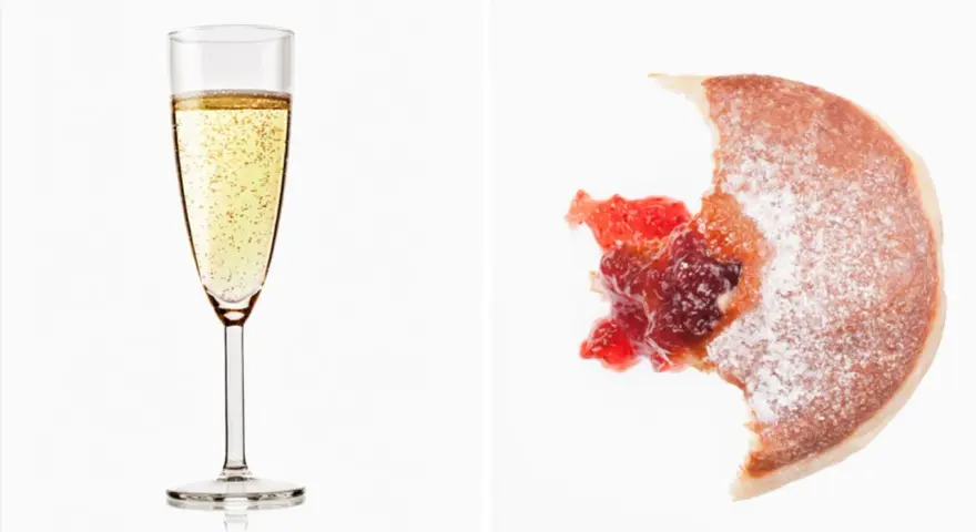 Sektglas mit Bläschen und ein angebissener Krapfen mit Marmelade. Wein Kalorien sind oft unterschätzt.